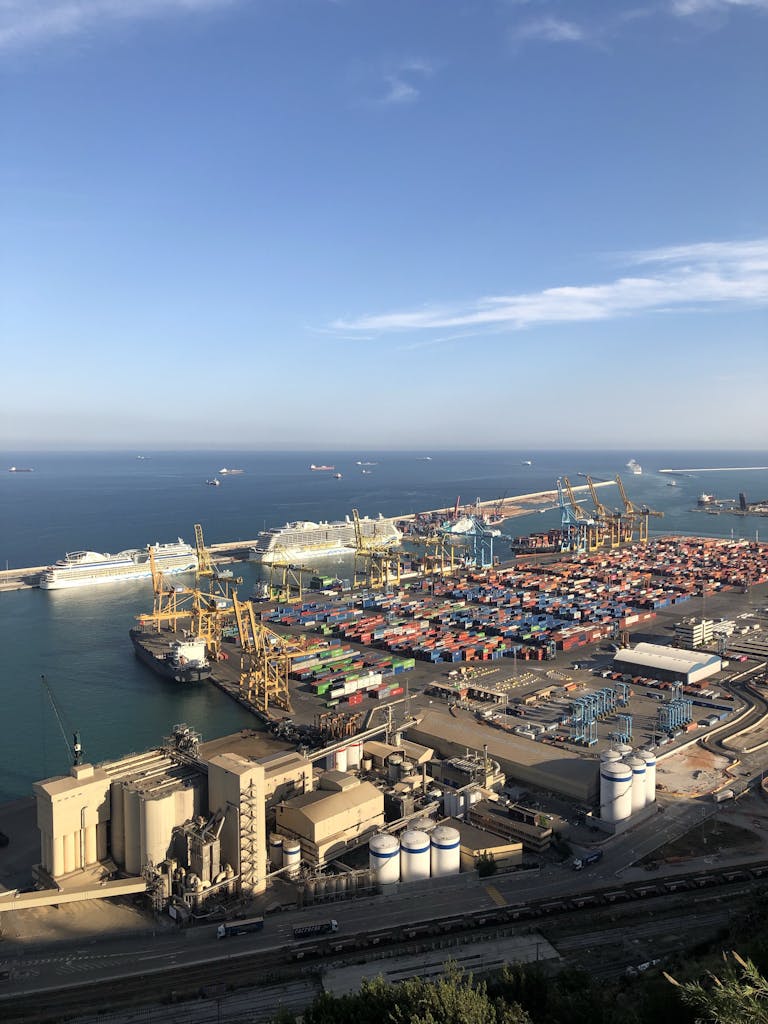 From above of modern loading harbor with cargo and infrastructure and seascape with ships floating on water in sunny day